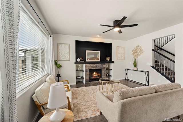 9869 Meridian Hills Trl, Peyton, CO 80831 - living room featuring dark wood-style flooring, ceiling fan, a stone fireplace, and stairway