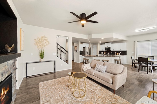 9869 Meridian Hills Trl, Peyton, CO 80831 - living room with stairs, a stone fireplace, dark wood-type flooring, and ceiling fan