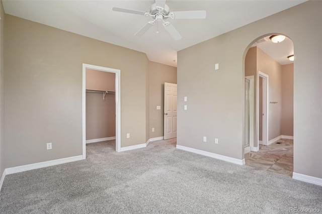 12921 Grant Cir Unit B, Thornton, CO 80241 - unfurnished bedroom with light colored carpet, arched walkways, a walk in closet, a ceiling fan, and baseboards