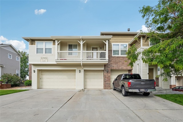 12921 Grant Cir Unit B, Thornton, CO 80241 - view of front of house featuring an attached garage, concrete driveway, a balcony, and brick siding