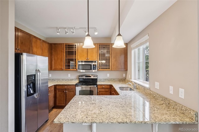 12921 Grant Cir Unit B, Thornton, CO 80241 - kitchen with stainless steel appliances, a peninsula, brown cabinetry, and light stone counters