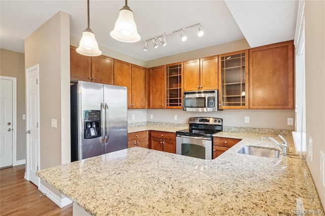 12921 Grant Cir Unit B, Thornton, CO 80241 - kitchen with appliances with stainless steel finishes, a peninsula, light stone countertops, brown cabinetry, and decorative light fixtures
