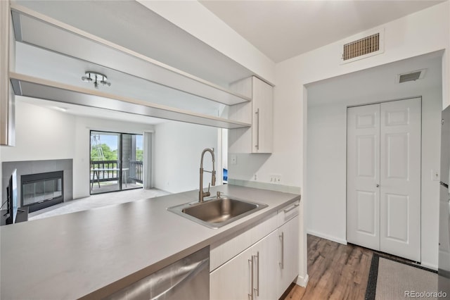2727 Folsom St Unit 303, Boulder, CO 80304 - kitchen with a sink, stainless steel dishwasher, light countertops, light wood-style floors, and a tile fireplace
