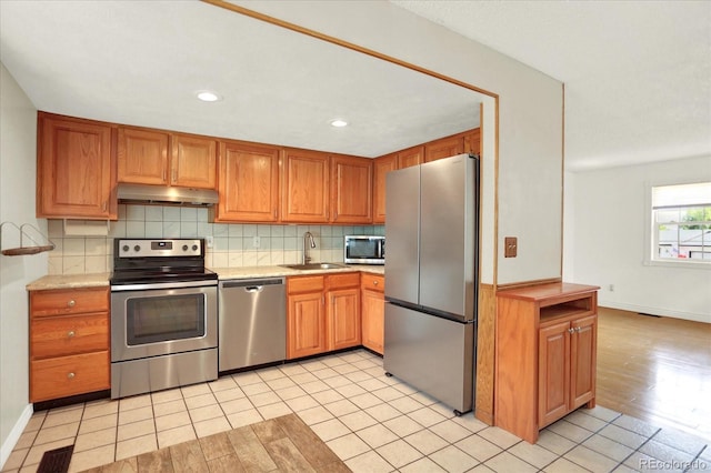13496 Alcott Way, Broomfield, CO 80020 - kitchen with appliances with stainless steel finishes, under cabinet range hood, a sink, light countertops, and backsplash