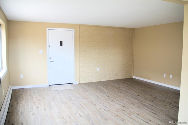 875 S Quebec St Unit 25, Denver, CO 80247 - unfurnished room with brick wall, a baseboard heating unit, wood finished floors, and baseboards