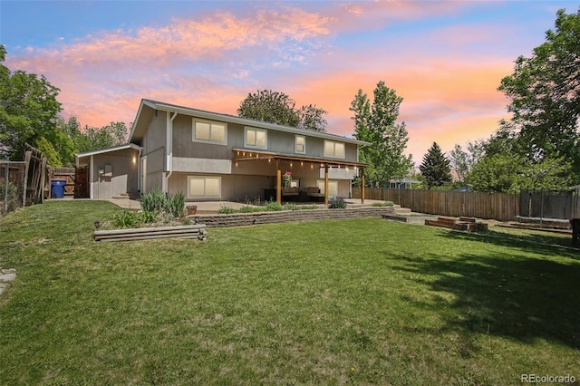 back of house at dusk featuring a vegetable garden and a trampoline