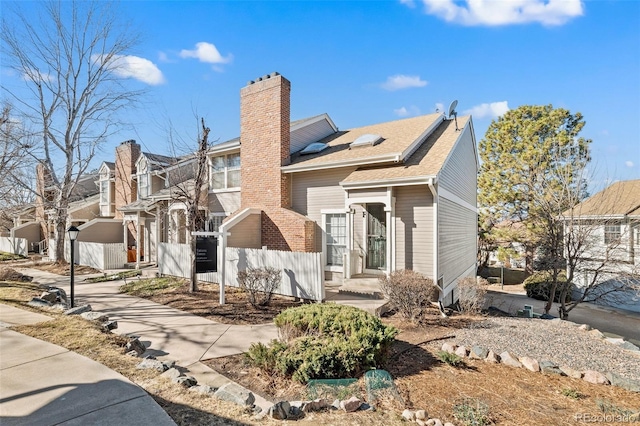 view of front facade with a chimney, fence, and a residential view