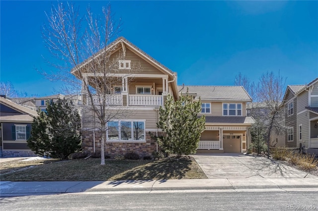 craftsman-style house with an attached garage, stone siding, driveway, and a balcony