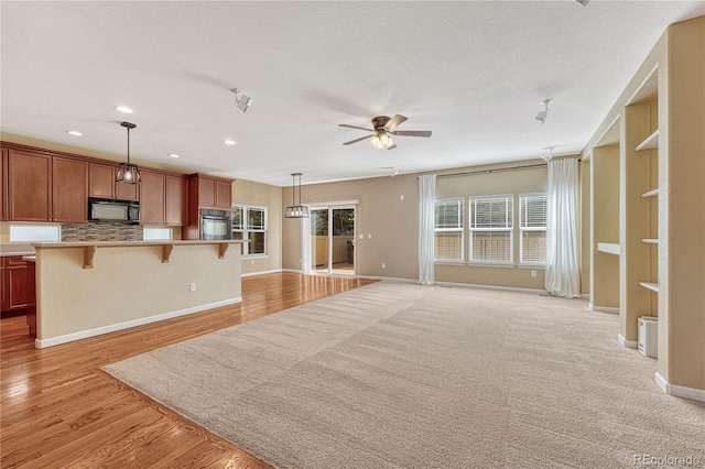 unfurnished living room with light wood finished floors, recessed lighting, a ceiling fan, a textured ceiling, and baseboards