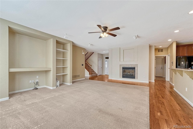 unfurnished living room featuring visible vents, baseboards, a tile fireplace, stairway, and recessed lighting