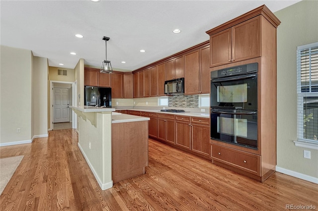 kitchen featuring light wood-type flooring, black appliances, light countertops, and decorative backsplash