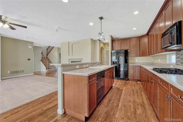 kitchen featuring light countertops, visible vents, open floor plan, a sink, and black appliances