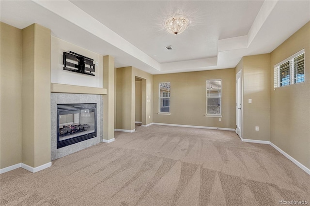 unfurnished living room with visible vents, baseboards, a raised ceiling, a tile fireplace, and carpet flooring