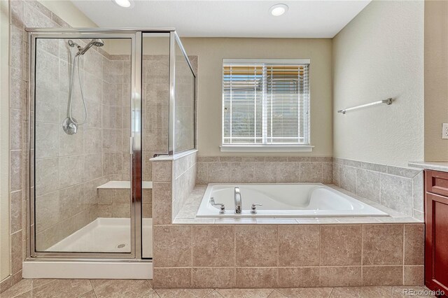 full bathroom featuring a garden tub, a shower stall, tile patterned floors, and vanity