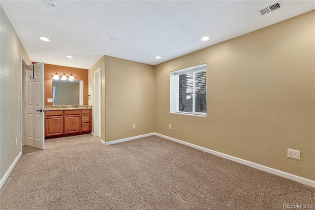 interior space with light carpet, connected bathroom, visible vents, and baseboards