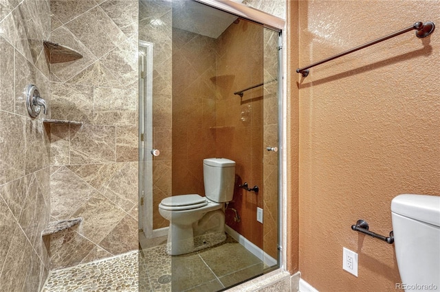 full bath with a textured wall, a shower stall, and toilet