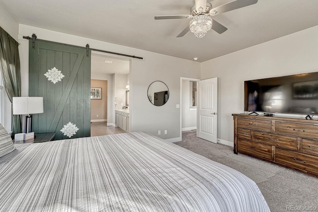 carpeted bedroom featuring ceiling fan, a barn door, and ensuite bath