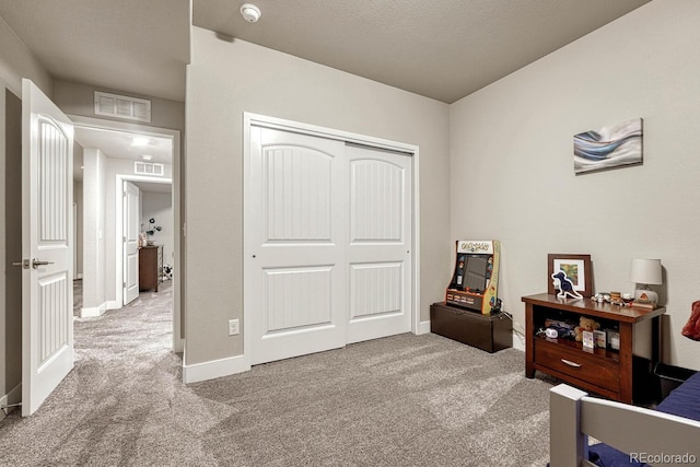 carpeted bedroom featuring a textured ceiling and a closet