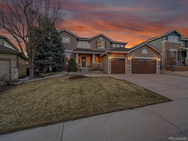 view of front facade with concrete driveway, a garage, a lawn, and stone siding