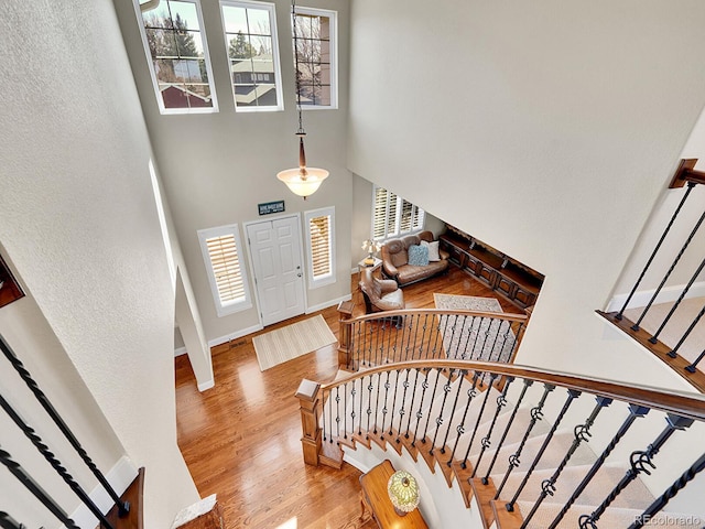 foyer entrance with baseboards, stairs, a high ceiling, and wood finished floors