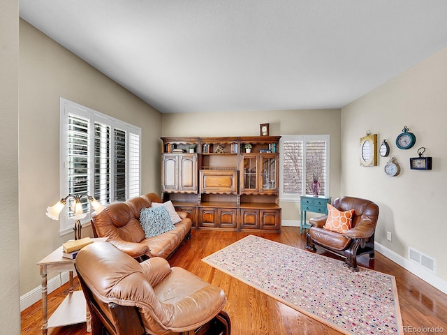 living room with a wealth of natural light, visible vents, and wood finished floors