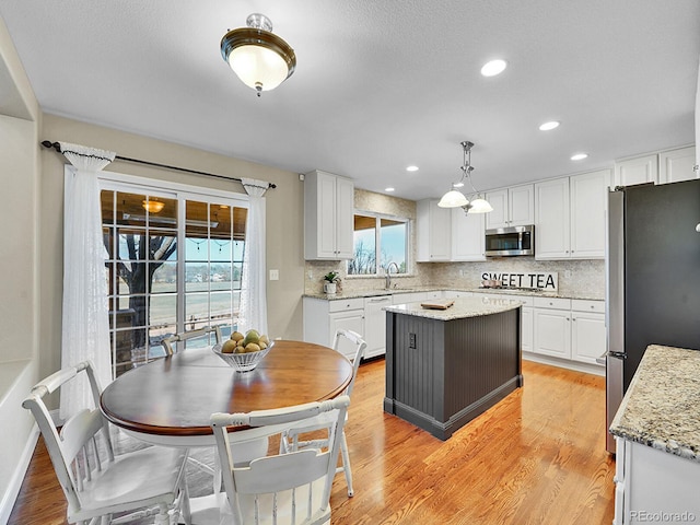 kitchen featuring decorative backsplash, white cabinets, appliances with stainless steel finishes, and light wood-style floors