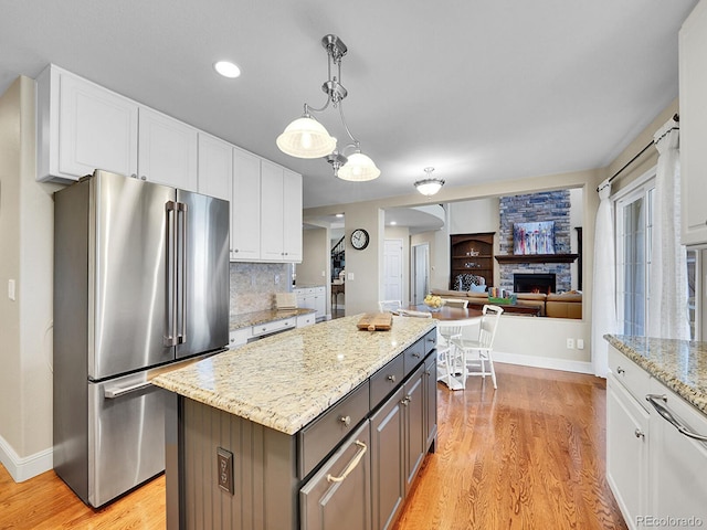 kitchen with white cabinets, a center island, freestanding refrigerator, and light wood-style floors