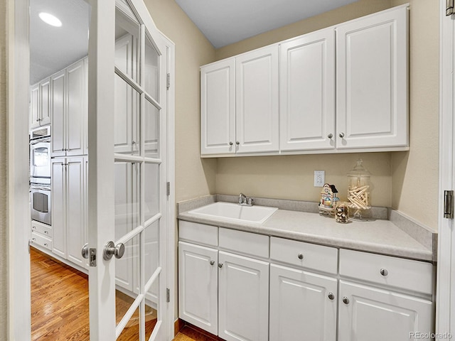 laundry area featuring a sink and wood finished floors