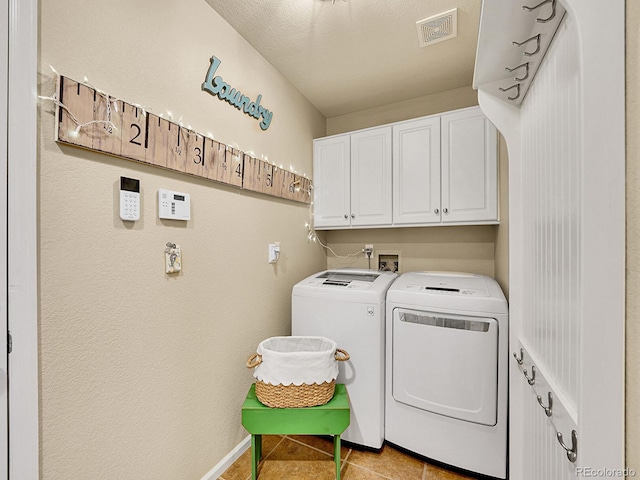 washroom with visible vents, baseboards, light tile patterned flooring, cabinet space, and separate washer and dryer