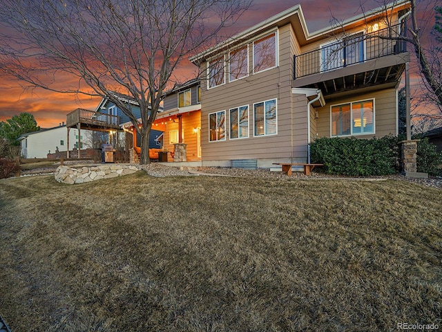 back of property featuring a balcony and a lawn