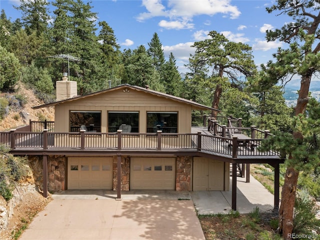 1141 Koral Ct, Estes Park, CO 80517 - view of front of home with stone siding, an attached garage, a chimney, driveway, and a deck