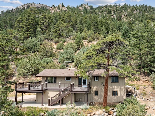 1141 Koral Ct, Estes Park, CO 80517 - rear view of house with a deck, stairs, a wooded view, a patio area, and roof with shingles