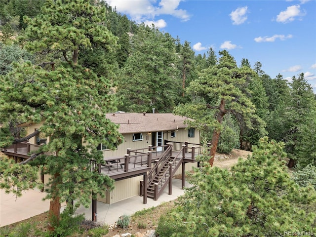 1141 Koral Ct, Estes Park, CO 80517 - rear view of house with stairway, a wooden deck, a forest view, roof with shingles, and a patio