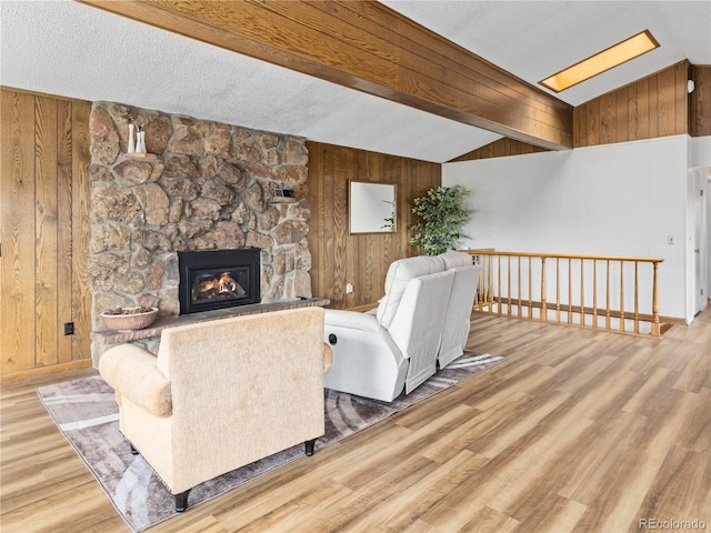 1141 Koral Ct, Estes Park, CO 80517 - living room featuring wooden walls, wood finished floors, a skylight, a stone fireplace, and baseboards