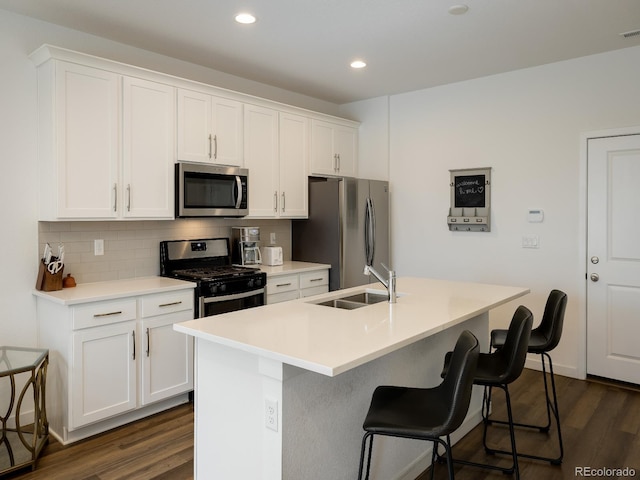 kitchen featuring stainless steel appliances, dark wood-type flooring, sink, and an island with sink