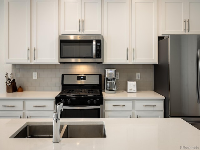 kitchen featuring stainless steel appliances, white cabinets, sink, and tasteful backsplash