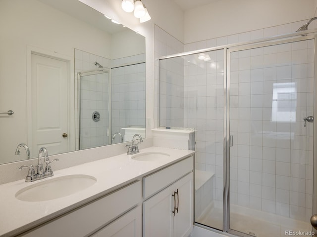 bathroom featuring a shower with shower door, double sink, and oversized vanity