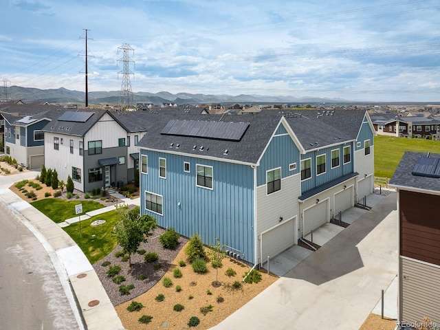 view of front of house with a front lawn, a garage, a mountain view, and solar panels