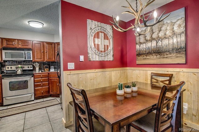 405 Four Oclock Rd Unit 15-A, Breckenridge, CO 80424 - dining area featuring a textured ceiling, a wainscoted wall, wood walls, and light tile patterned flooring