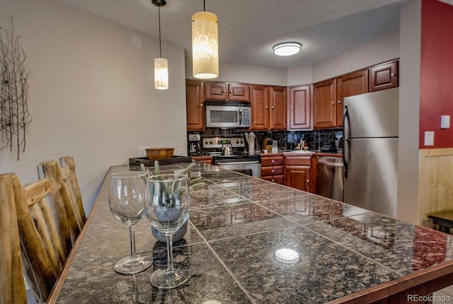 405 Four Oclock Rd Unit 15-A, Breckenridge, CO 80424 - kitchen featuring appliances with stainless steel finishes, tile counters, a peninsula, backsplash, and pendant lighting