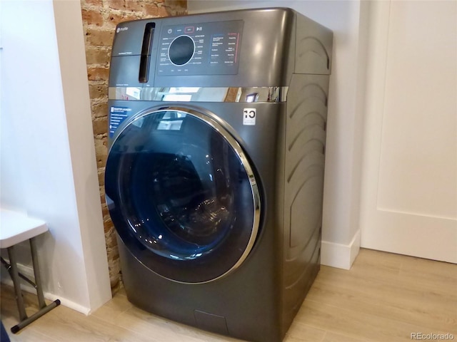 laundry area featuring laundry area, baseboards, washer / clothes dryer, and wood finished floors