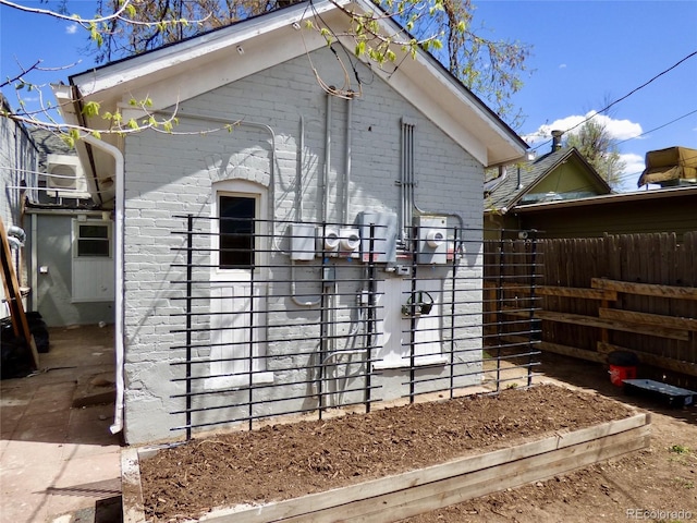 view of side of property featuring brick siding and fence