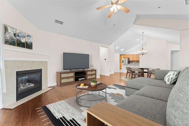 living room with hardwood / wood-style flooring, lofted ceiling, and ceiling fan with notable chandelier