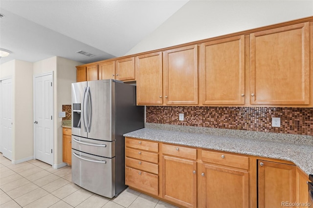 kitchen featuring light stone countertops, lofted ceiling, decorative backsplash, and stainless steel fridge with ice dispenser