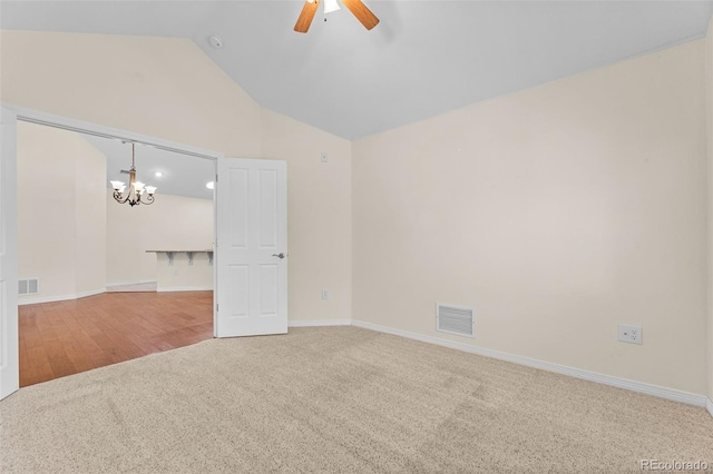 spare room featuring lofted ceiling, hardwood / wood-style floors, and ceiling fan with notable chandelier