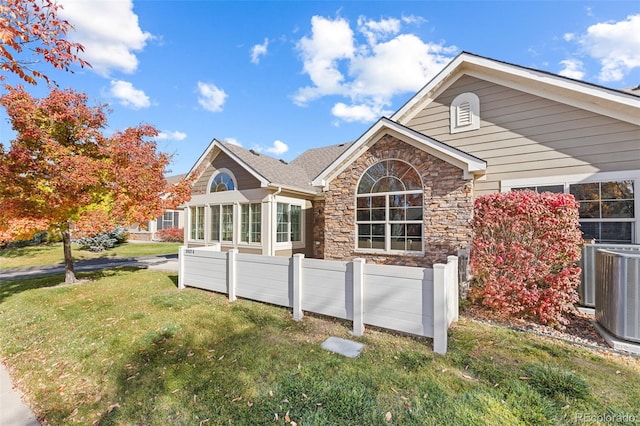 rear view of house featuring a lawn and central AC unit