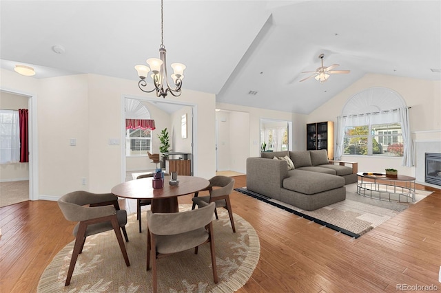 dining space with wood-type flooring, vaulted ceiling, and ceiling fan with notable chandelier