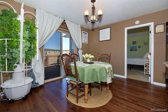 dining room featuring dark wood-type flooring, a notable chandelier, and baseboards