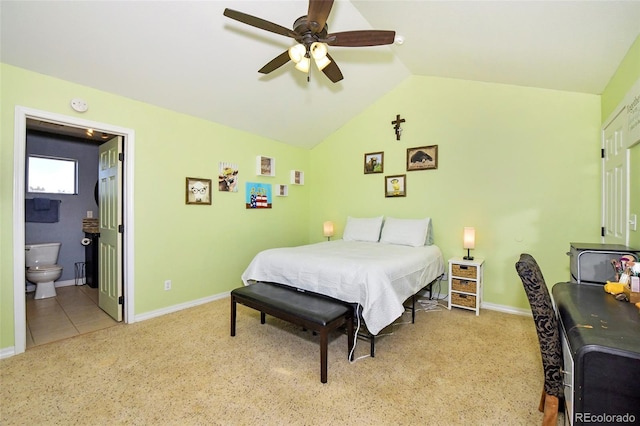 bedroom featuring light carpet, vaulted ceiling, ceiling fan, ensuite bath, and baseboards