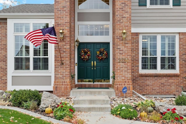 view of exterior entry with brick siding, a shingled roof, and french doors